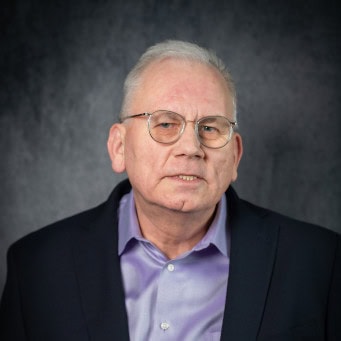 Headshot of Tim Burkart wearing a navy blue sport coat and lavender shirt. Tim is the founder of Dot832 Digital Inc.